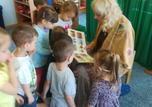 Dzieci zgromadzone wokół aktorki, oglądają obrazki w książce.